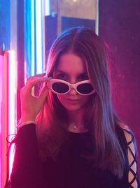 Portrait of young woman wearing sunglasses at nightclub