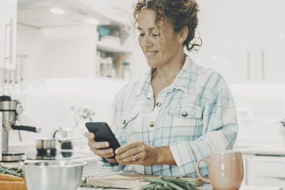 Young woman using mobile phone while sitting at home