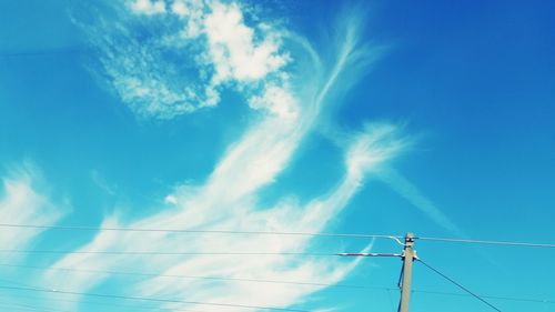 Low angle view of electricity pylon against blue sky