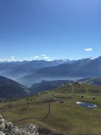 Scenic view of field and mountains against blue sky