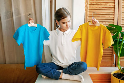 Girl chooses t-shirt among clothes at home. mockup friendly. t-shirts ready to have design