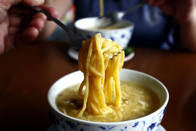 Close-up of hand holding soup in bowl