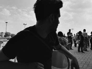 Friends looking at man standing on street against sky
