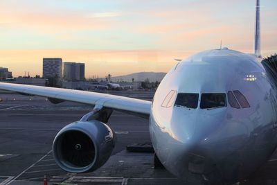 Airplane on runway against sky during sunset