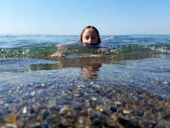 Portrait of girl swimming in sea against sky