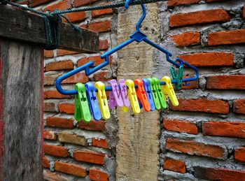 Multi colored clothespins hanging on brick wall