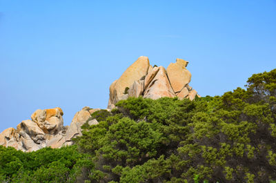 Low angle view of rocks against clear blue sky