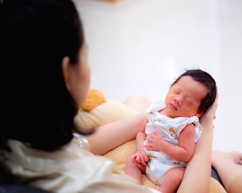 Close-up of woman holding newborn baby girl on bed at home