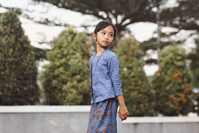 Portrait of young woman standing against trees