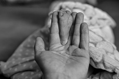 Cropped hand of father holding baby foot at home