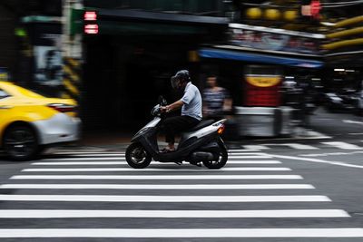 Blurred motion of man riding motorcycle on city street