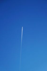 Low angle view of vapor trail against clear blue sky