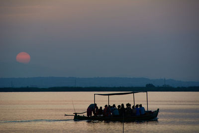 People in boat against sky during sunset