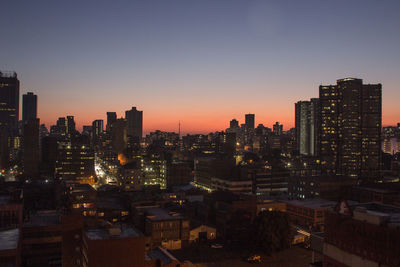 Illuminated cityscape against sky during sunset