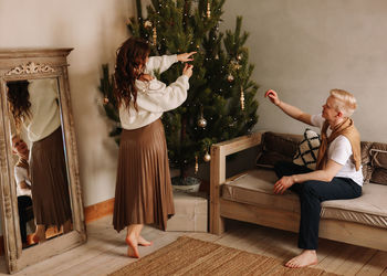 A man and a woman in love embrace give gift gifts celebrate a holiday at the christmas tree at home