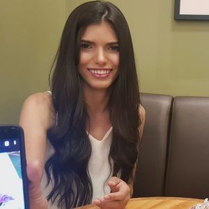 Portrait of smiling young woman showing mobile phone at home