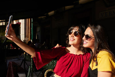 Portrait of smiling young woman using mobile phone outdoors