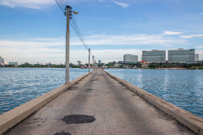 Pier over river against sky in city