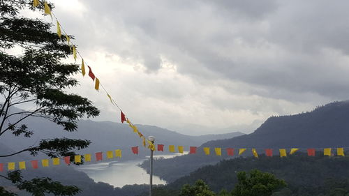 Multi colored flags hanging on mountain against sky