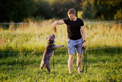 Side view of man with dog on field