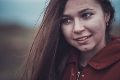 Close-up of smiling woman looking away while standing outdoors