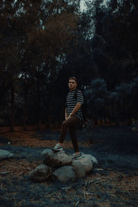 Full length of boy standing on rock in forest