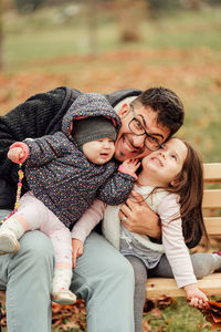 Full length of father and daughter sitting outdoors