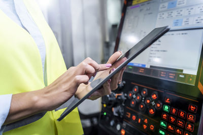 Hands of engineer using tablet pc by machine in industry