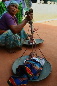 Senior woman measuring baby girl on weight scale