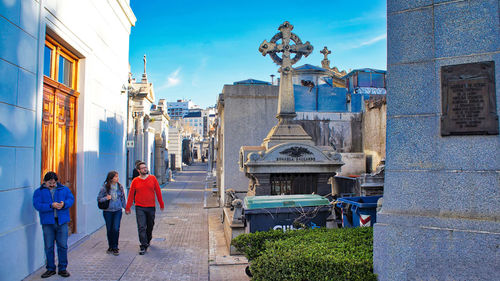 Rear view of people walking on street against buildings in city