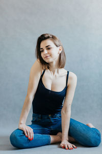 Portrait of a young woman sitting against wall