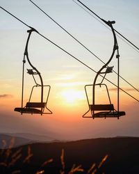 Low angle view of silhouette electricity pylon against sky during sunset
