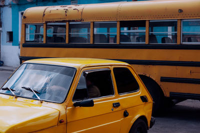 Retro yellow vintage car and yellow school bus on city street with old buildings