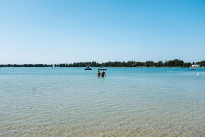 People in water against clear sky