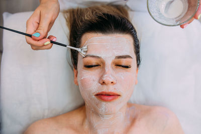 Cosmetologist makes cleansing peeling and face mask for woman. beauty skin care