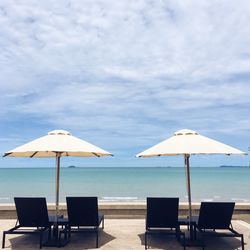 Deck chairs on beach against sky