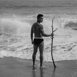 Full length of shirtless man standing on beach