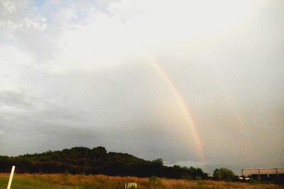 Scenic view of rainbow over field against sky