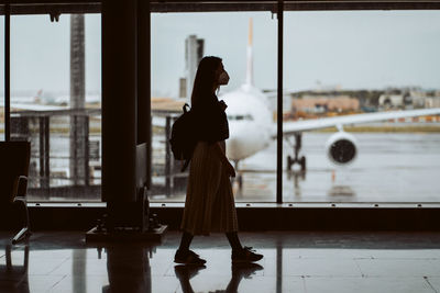 Side view of woman standing by window