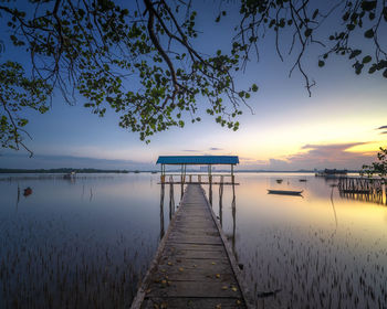 Pier over lake against sky during sunset