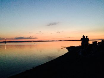 Silhouette people on beach against sky during sunset