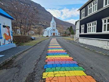 Empty road by building against sky