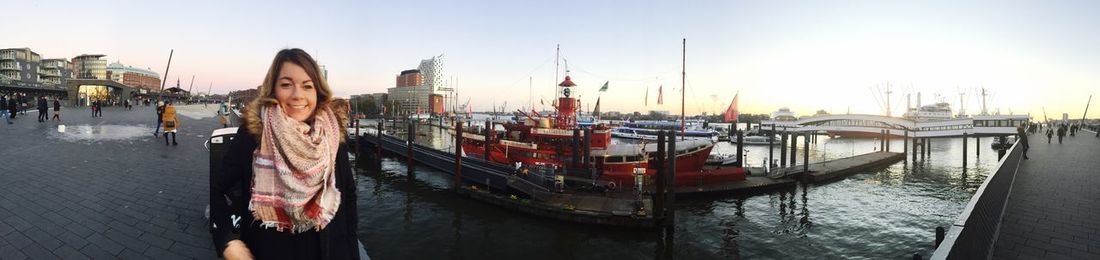 Panoramic shot of young woman standing in harbor against clear sky