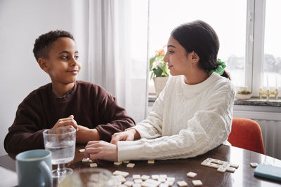 Girl and boy playing scrabble at dining table