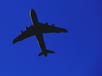 Low angle view of airplane against clear blue sky