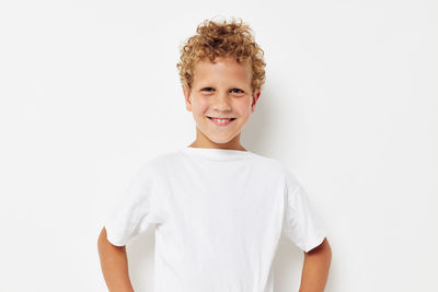 Portrait of smiling boy standing against white background