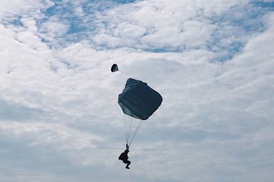 Low angle view of person paragliding against sky