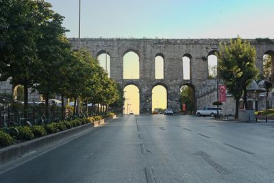 Road by trees against sky in city