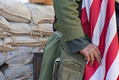 Midsection of man with flag against sack heap