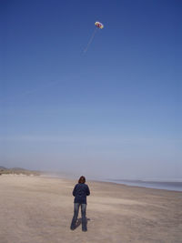 Full length of man standing on beach against clear blue sky
